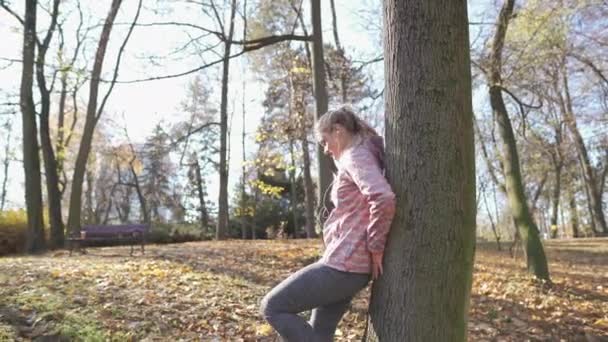 Una mujer joven abraza un tronco de árbol en un día soleado. — Vídeos de Stock