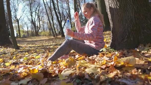 Atraktivní dívka se napila vody a položila láhev na zem.. — Stock video