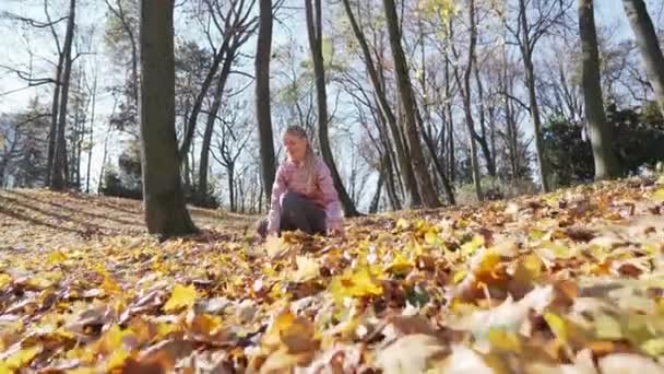 Žena šťastně vyhazuje podzimní barevné listí do vzduchu. — Stock video