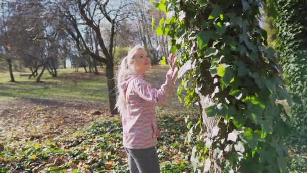 A girl walks around an ivy-covered tree. — стоковое видео