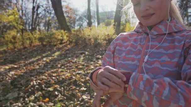 During a short running break, a girl checks her time. — Vídeo de stock