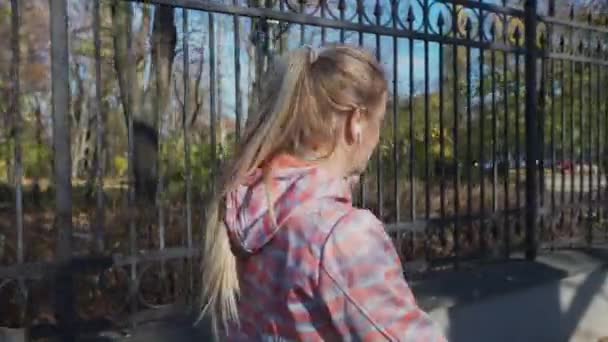 Őszi reggelen sétálva egy nő csuklyát rak a fejére.. — Stock videók
