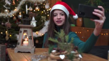 Bir genç cep telefonuyla konuşur ve Noel ağacını gösterir..