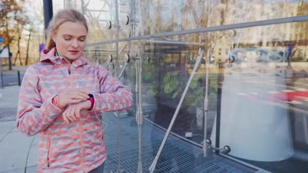While walking, a woman on a smartwatch checks her heart rate and blood pressure. — Stockvideo