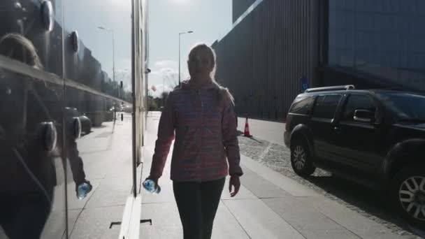 A girl drinks water on a sunny day while walking. — стоковое видео