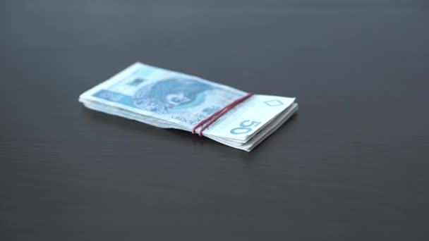 Деньги, связанные резиновой лентой, падают на стол сверху. — стоковое видео