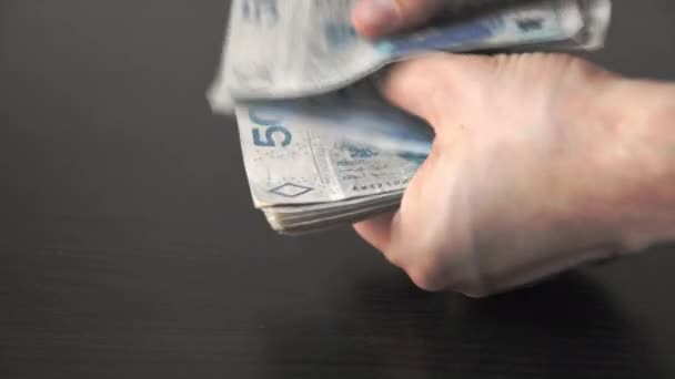 En sus manos, el hombre cuenta cincuenta billetes de zloty polacos. — Vídeo de stock