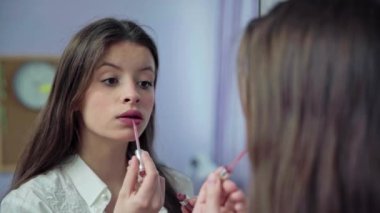 Evde aynanın önünde kendini boyayan dudaklar. Uzun ve dağınık saçlı genç esmer..