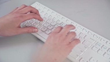 Kadınların elleri bilgisayar klavyesine yazı yazar. Siyah harfli ve numaralı beyaz klavye. Bilgisayar aksesuarlarının modern tasarımı.