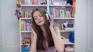 Genç bir esmer sesini çalışmak için müzik dinlerken şarkı söylüyor. Evde yetişmiş bir şarkıcı, favori grubuyla evde kulaklıkla şarkı söyleme alıştırması yapıyor..