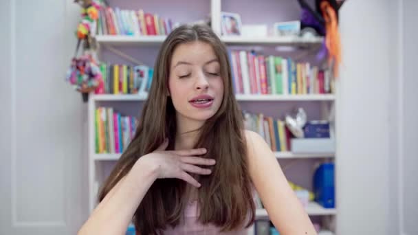 Nastolatka Śpiewa Gesty Bezpośrednio Przed Kamerą Siedząc Domu Tle Biblioteczki — Wideo stockowe