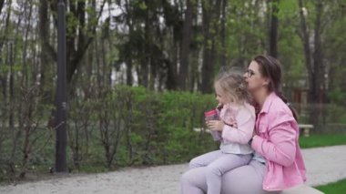 A girl sits on her lap at her nannys house and she shows her what can be observed in spring in the city park. A sunny spring day.