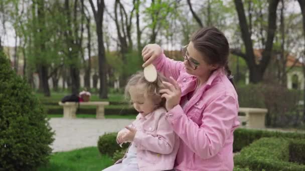 Mother Sits Her Daughter City Park Spring Season Combing Blonde — Stockvideo