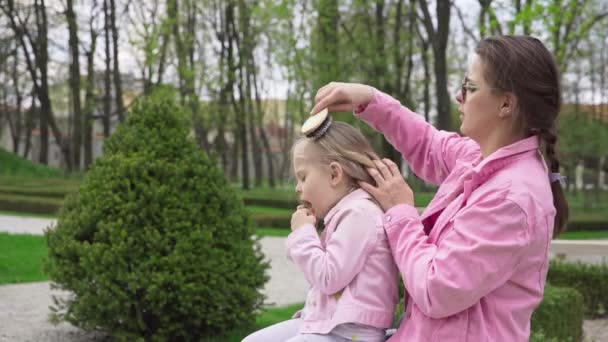 Matka Siedzi Córką Parku Miejskim Sezonie Wiosennym Przeczesywanie Blond Włosów — Wideo stockowe