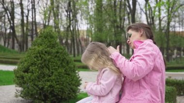 Genç bir anne kızlarının sarı saçlarını dikkatlice tarıyor. Çocuk şehir parkında dadısıyla birlikte kucağında oturuyor. Baharın ilk günlerinde.