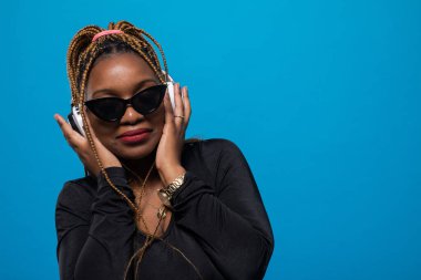 Şık güneş gözlükleri. Koyu tenli bir öğrenci kablosuz kulaklıkla müzik dinler. Müzikal rahatlama.