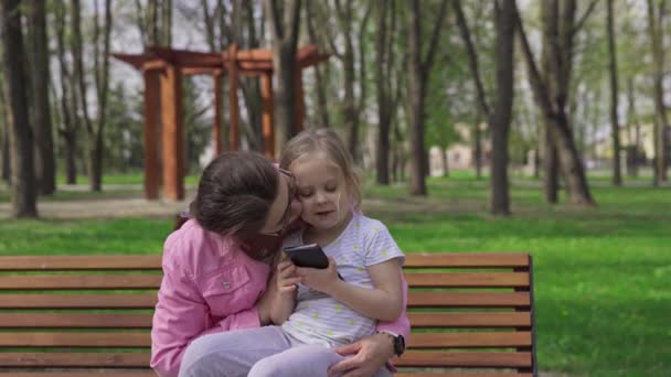 Tender Parental Kisses Mother Daughter Leisure Bench City Park Sunny — Video Stock