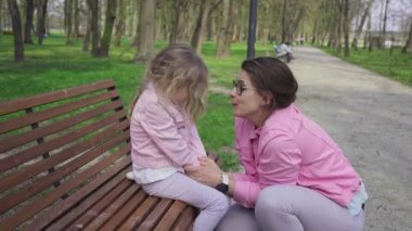 A caregiver explains to a girl how to behave in a city park. Talking to a child about serious matters with a smile on his face.