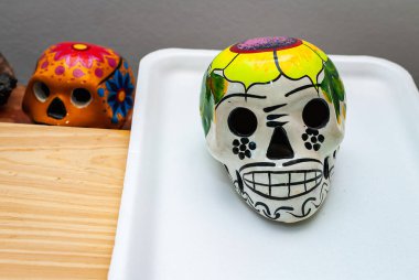 Meksika Ölüler Günü için çiçekli beyaz boyalı insan kafatası. Renkli arka plan, seçilmiş odak.