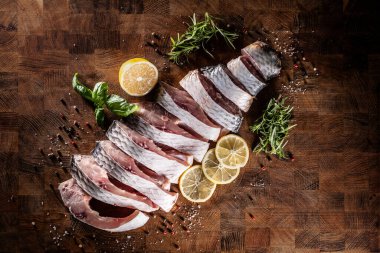 Porsiyonlu balık sazan balığı, tuzlu limon ve mutfak tahtasının üzerinde bitkiler..