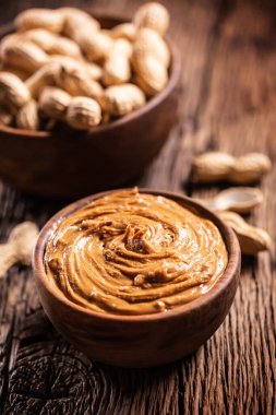 Ahşap kasede fıstık ezmesi ve sade meşe ağacında fıstık..