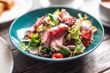 İnce dilimlenmiş biftek havuç, vişneli domates ve turplu gevrek bir levrekte servis edilir..