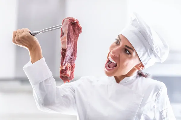伦敦的女厨师假装想咬一口她拿着叉子的生吃的红肉 — 图库照片
