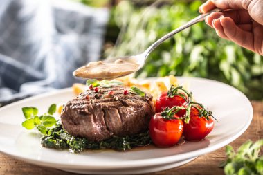 Pişmiş bifteğin üzerine sebze dökmeden önce soslu kaşık detayı..