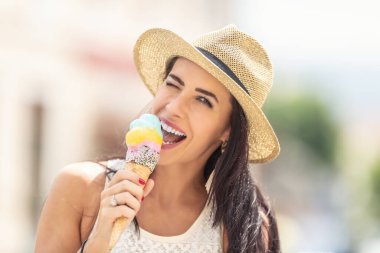 Güzel, mutlu bir kadın sıcak bir yaz gününde dondurma yalar..