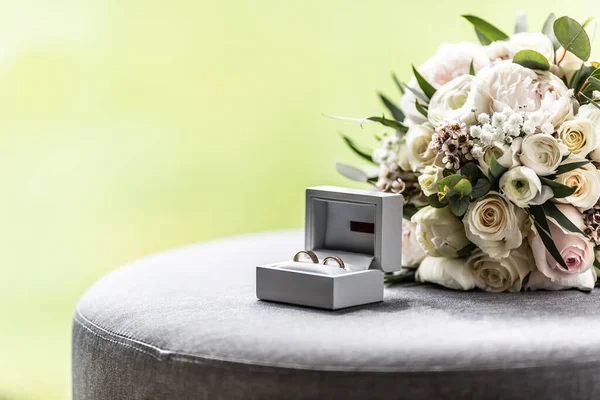 Open box with wedding rings placed next to a bouquette during a wedding.