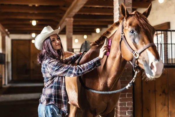 Ładna Kowbojka Grzebie Brązowego Konia Farbą Uśmiechając Się Stojąc Stajni — Zdjęcie stockowe