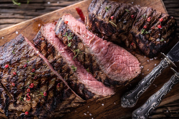 Grilled beef steak cut on a butcher board - Top of view.