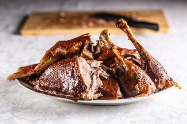 Portioned roast goose on a white plate - Close up.