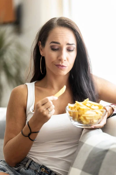 Woman hesitates about eating french fries due to unhealthy food effect of this diet.