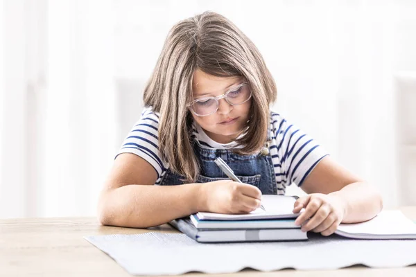 Bored Girl Writes Homework Exercise Book — стоковое фото