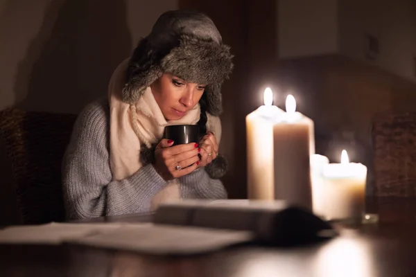 여자는 정전으로 전기가 나가기 때문에 찻잔에 따뜻하게 촛불을 — 스톡 사진