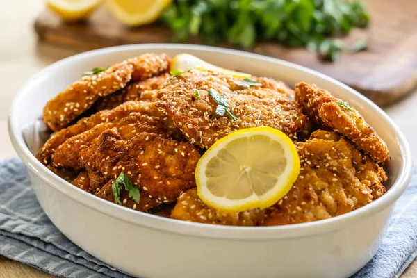 Juicy and crispy breaded meat as schnitzels are served with a slice of lemon.