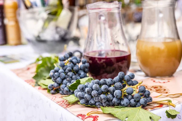 Fresh red grapes with jars of red wine and a traditional young wine burciak - burcak.
