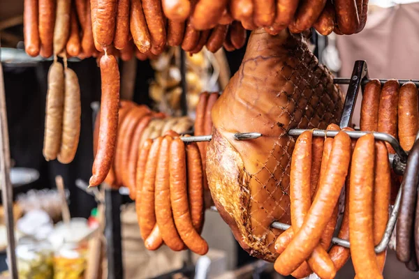 Cured meat products such as ham, sausages and frankfurters hanging at the market vendor booth outdoors.