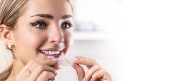 Diş sağlığı kliniğinde diş teli tutan mükemmel dişleri olan güzel genç bir kadının portresi..