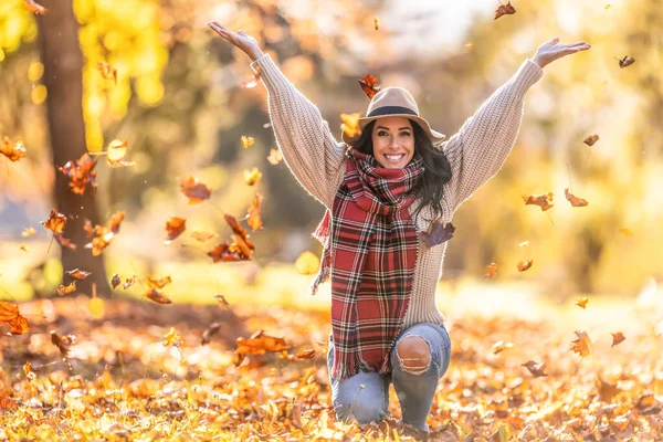 Parkta mutlu bir genç kadın Hint yazında yaprak atar ve sonbaharın tadını çıkarır..