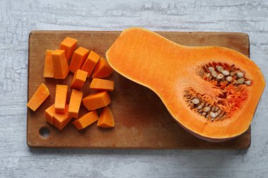 Kesme tahtasında soyulmuş ve kesilmiş kırmızı balkabağı..