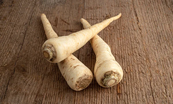 Üç maydanoz kökü kaba ahşap bir masada yatıyor. Seçici odak.
