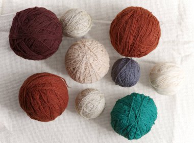 Kaba kumaşın arka planına karşı farklı renklerde iplik topları.