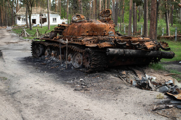 Сожженный русский танк возле дома, в который он стрелял. Война на Украине. Киевская область Селективный фокус.