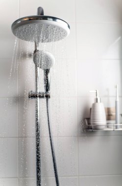 Duş kabininden temiz su fışkırıyor. Seçici odak.