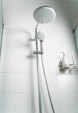 Duş kabininden temiz su fışkırıyor. Seçici odak.