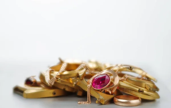A scrap of gold. Old and broken jewelry, coins, watches of gold and gold-plated on a white background. In soft focus. Selective focus.