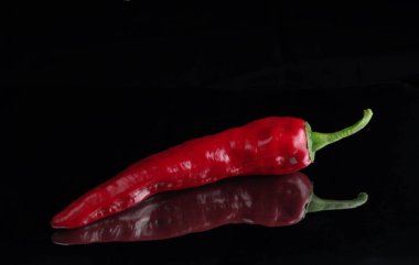 Aynada siyah bir yüzey üzerinde kırmızı biber. Seçici odak.