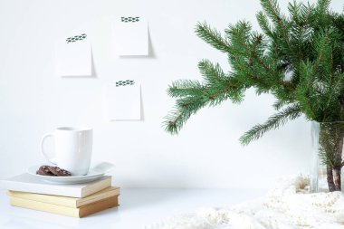 Kahvaltı hala hayat dolu. Kurabiyeli kahve, kitap ve vazo ve köknar dalları. Boş not defterleri beyaz duvara asılıydı. Noel süsü.
